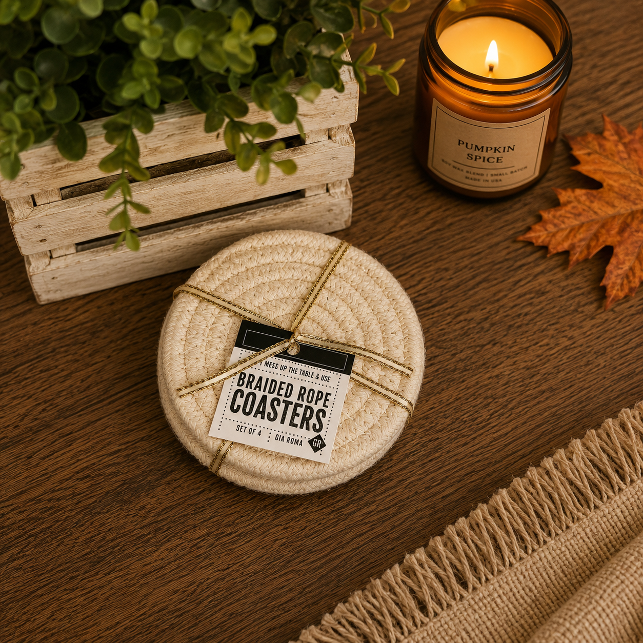 Braided rope coasters with a label on a wooden surface next to a candle and plant.