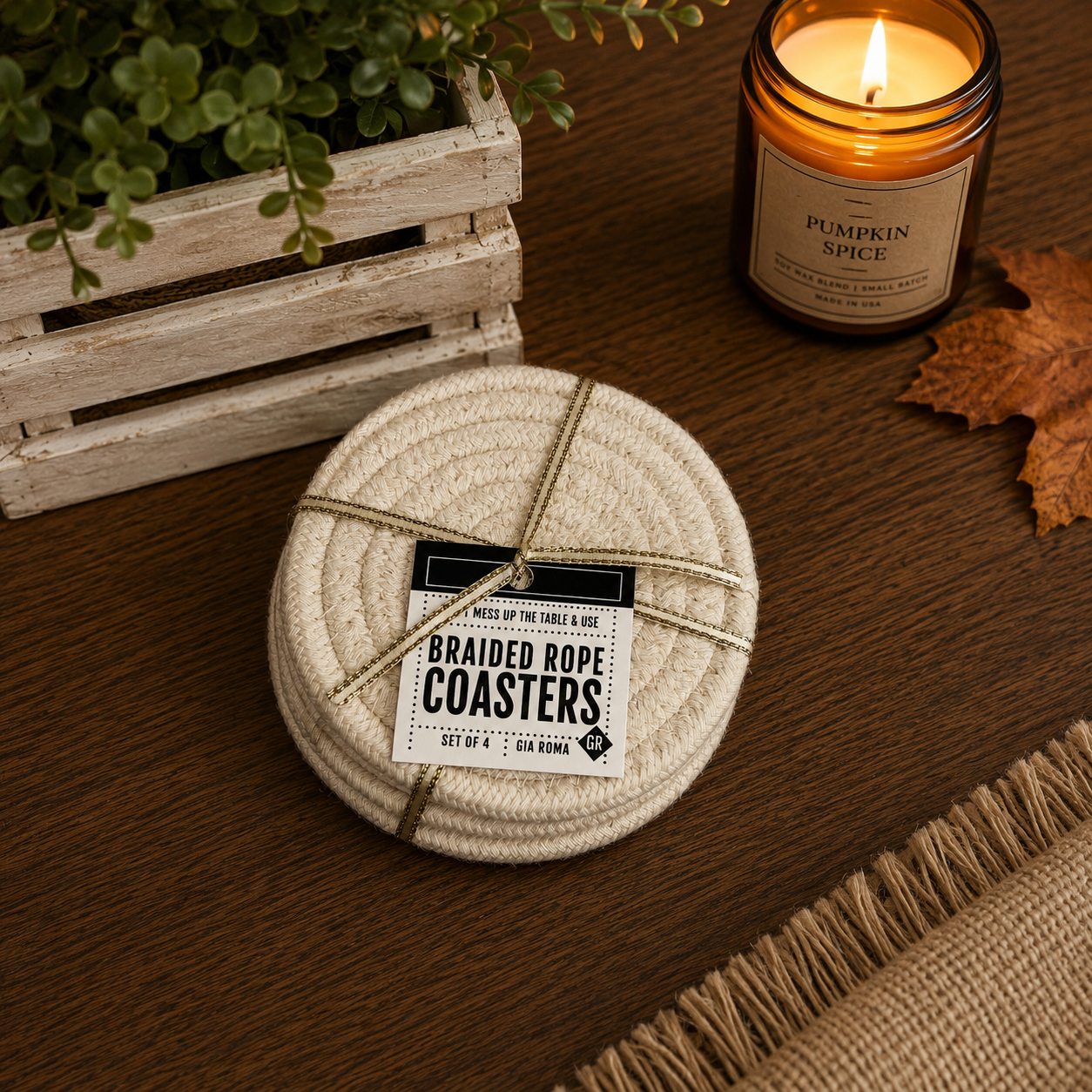 Branded rope coasters on a wooden surface with a lit candle and plant in the background
