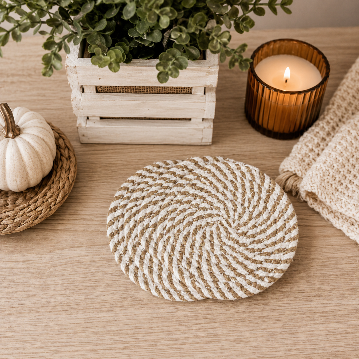 Round woven mat on a wooden surface with a candle, pumpkin, and plant in the background.