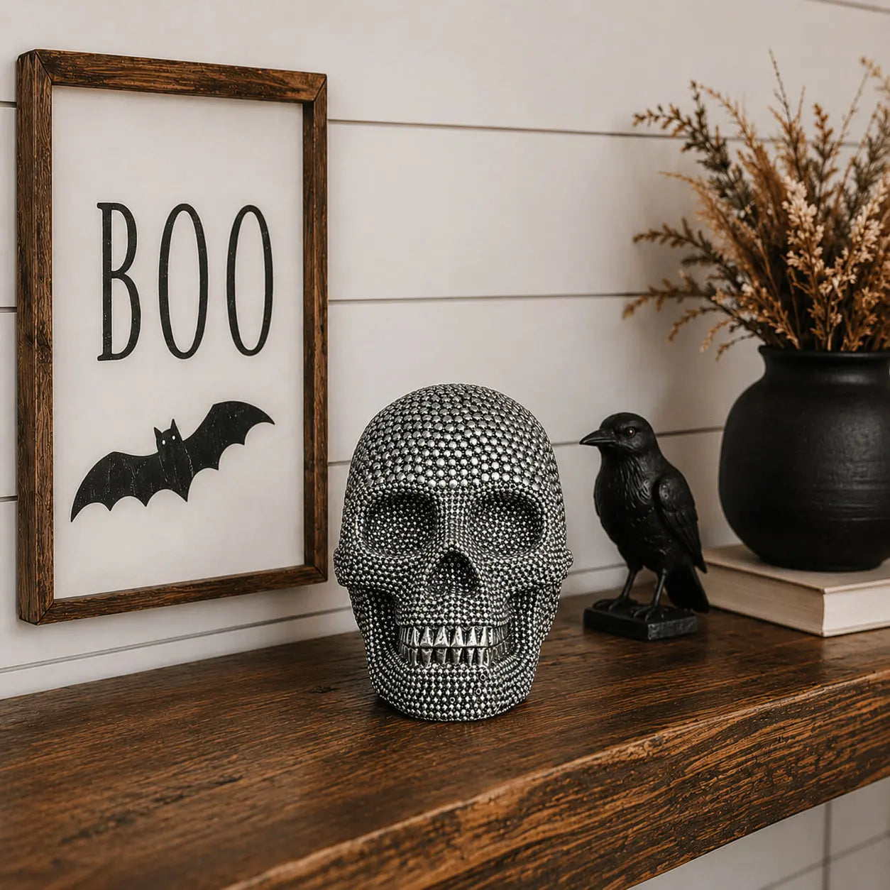 Decorative skull on a shelf with 'BOO' sign and bird