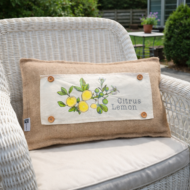 Decorative pillow with lemon design and 'Citrus Lemon' text on a wicker chair outdoors.