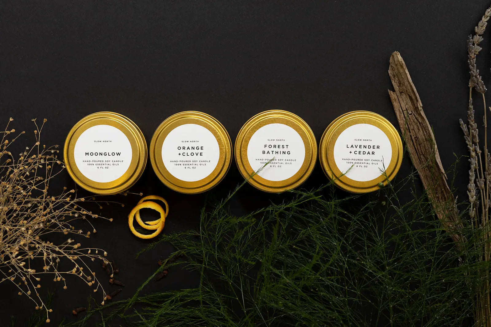 Four gold-tin soy candles with dried herbs and botanicals, perfect for cozy farmhouse home decor and relaxation.