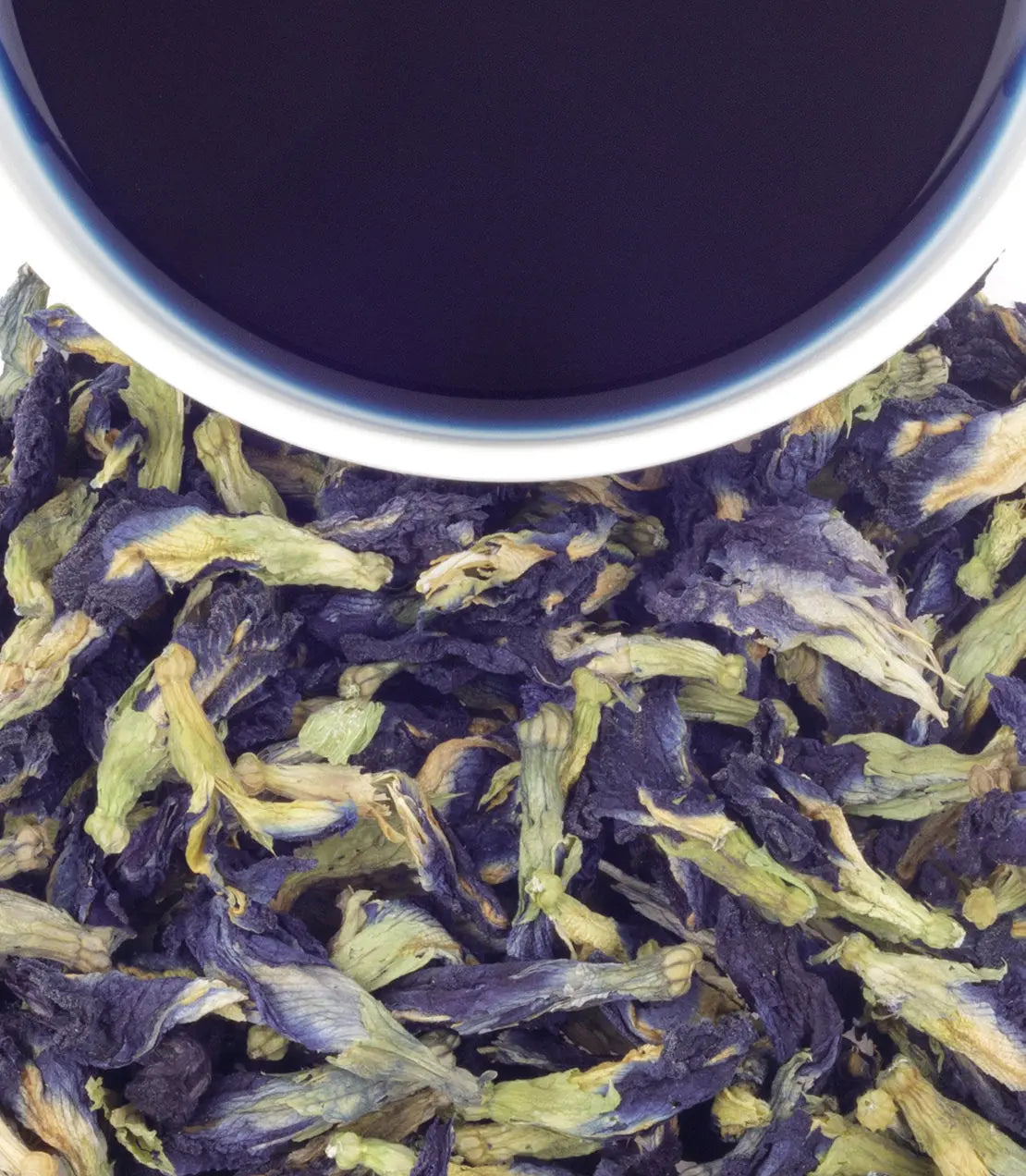 Close-up of butterfly pea flowers with a dark blue cup in the background