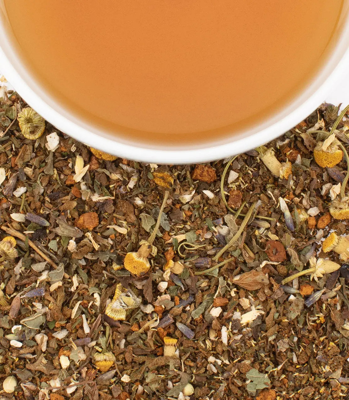 Tea leaves with a cup of tea in the background