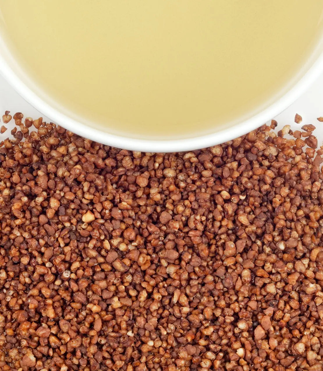 Close-up of roasted coffee beans with a cup of coffee in the background