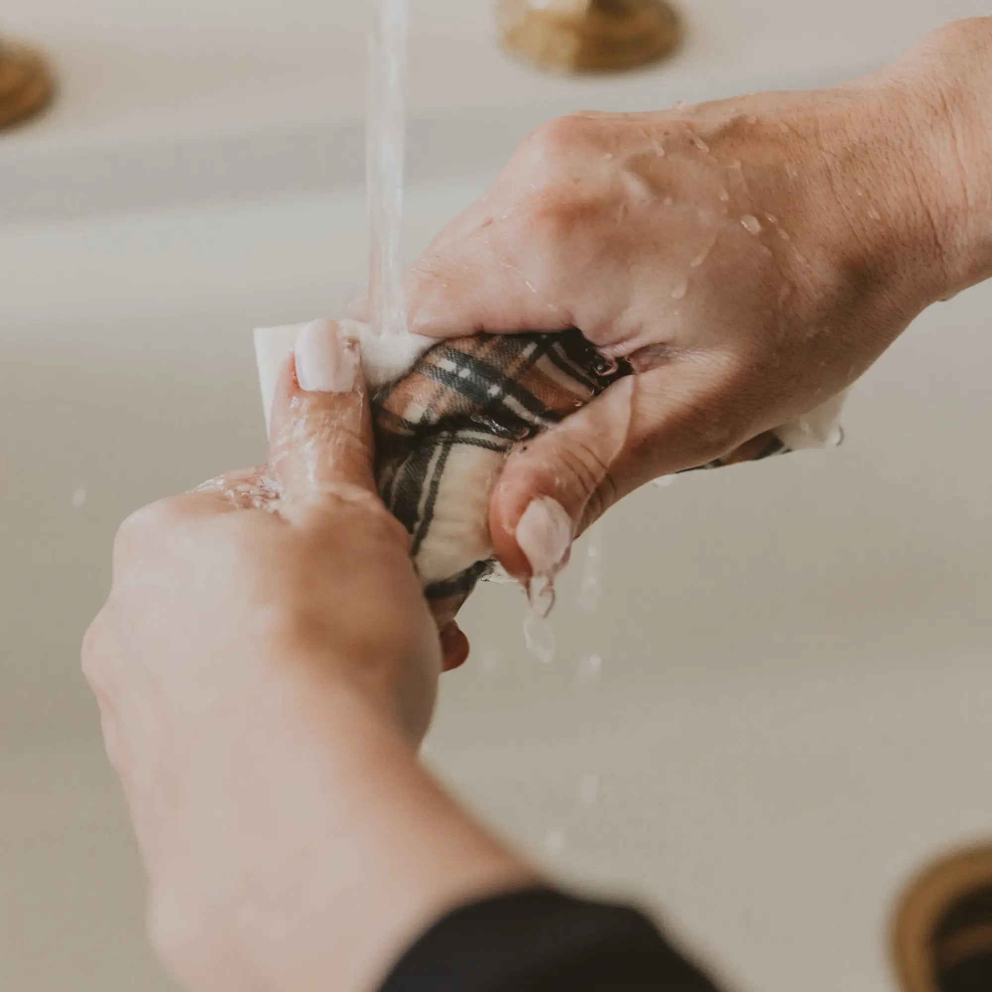 Person washing a fish under running water with a blurred background