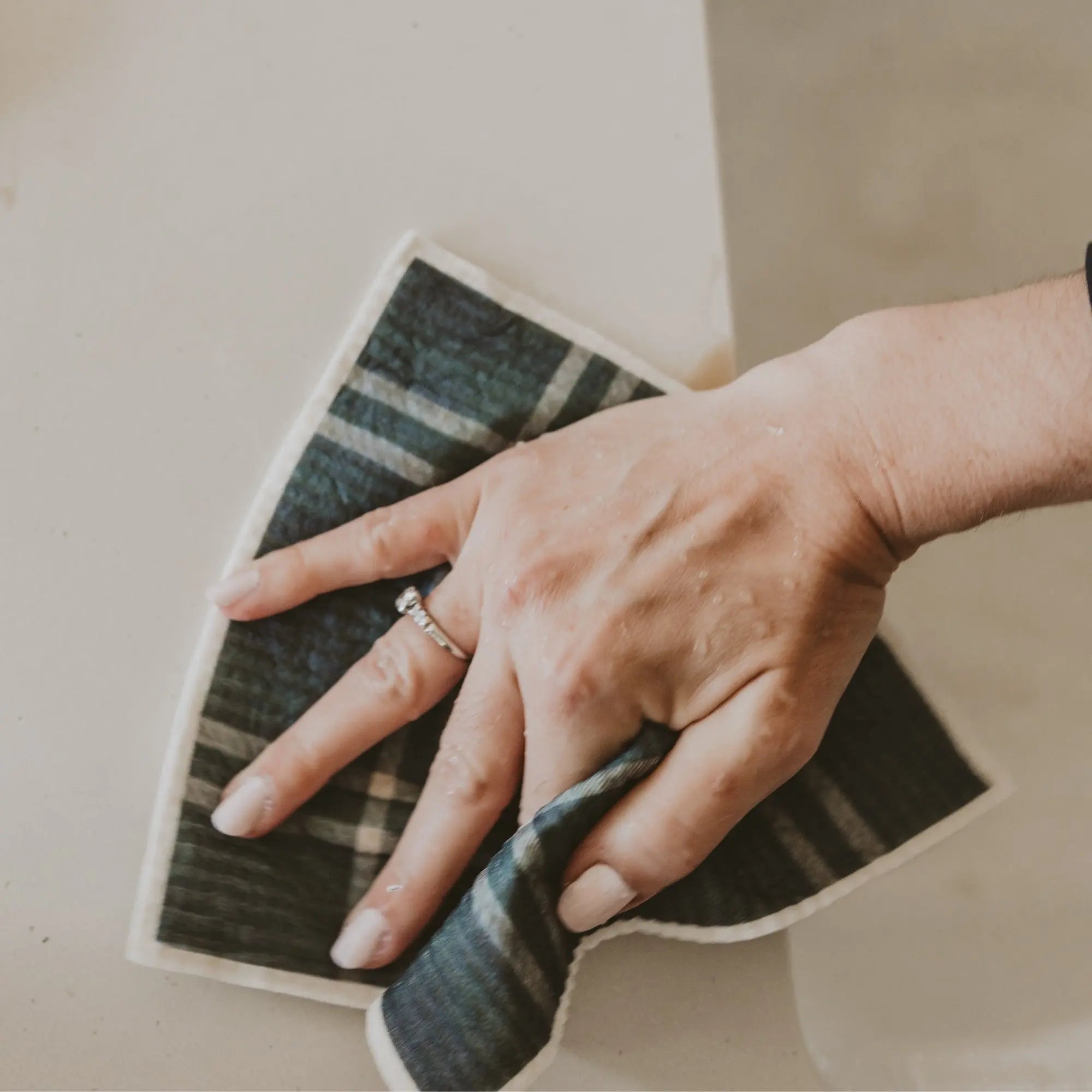 Hand using a green microfiber cloth to clean a surface