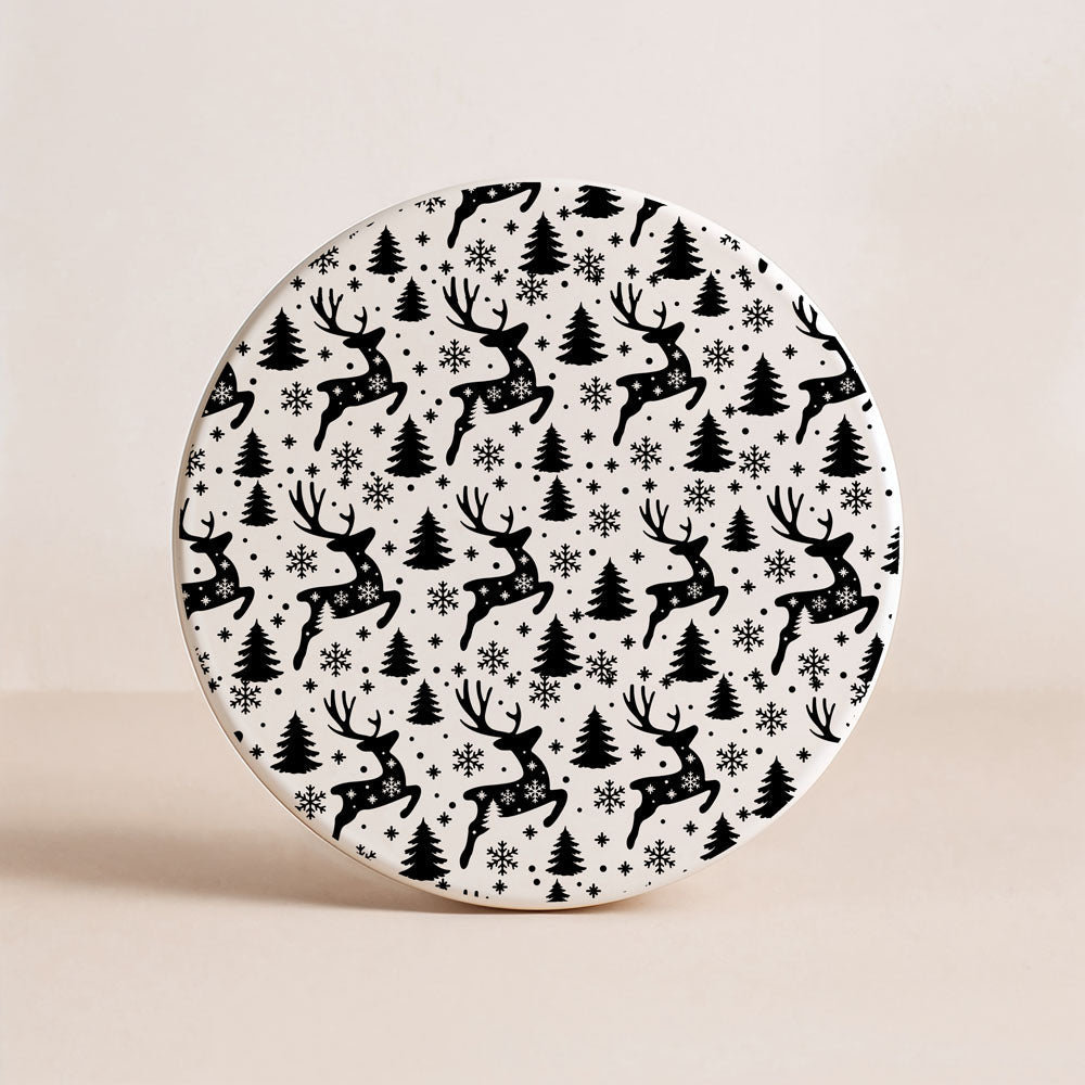 Round ceramic plate with black reindeer and tree pattern on a beige background
