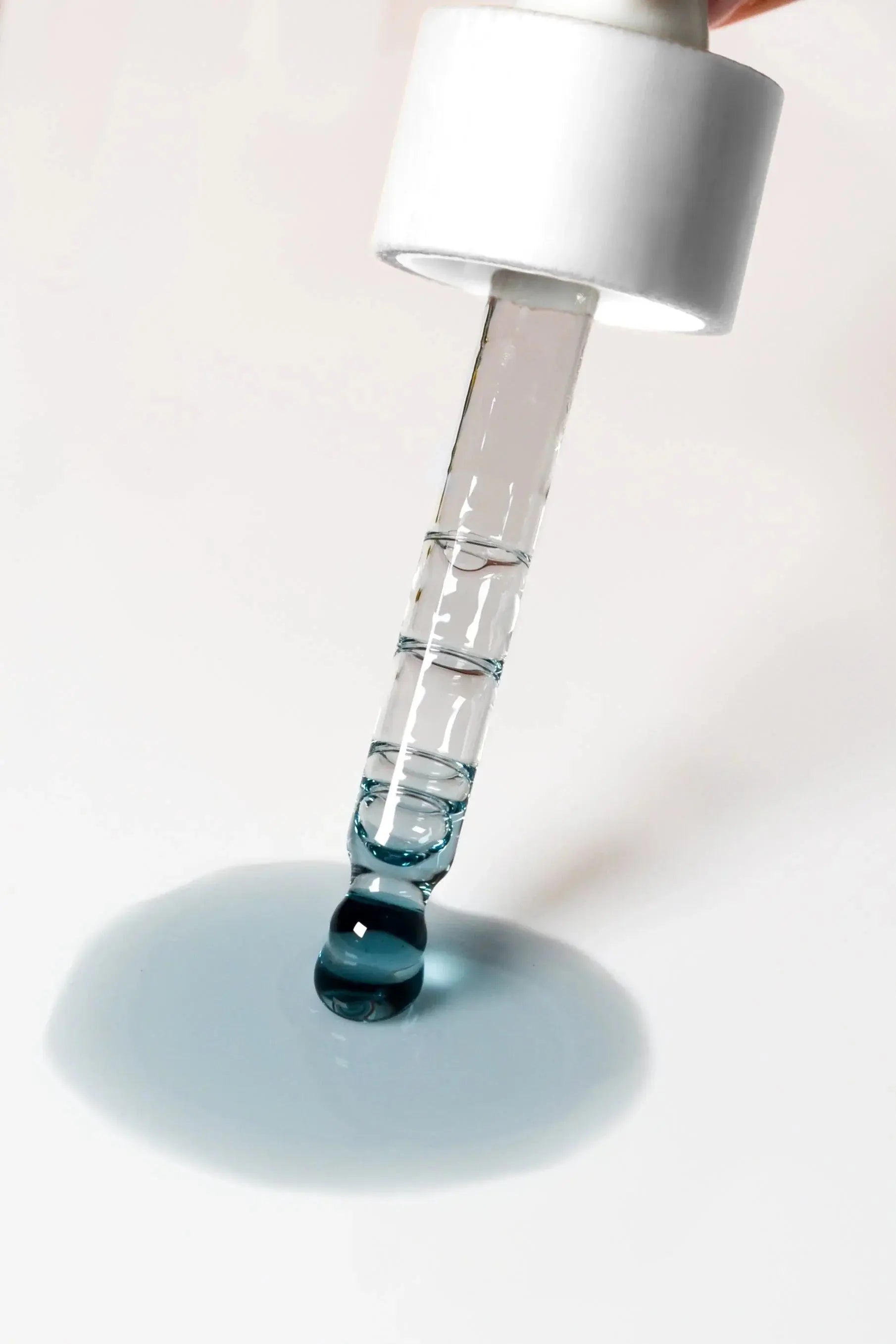 Clear glass dropper with blue liquid, perfect for bath essentials and home spa routines.