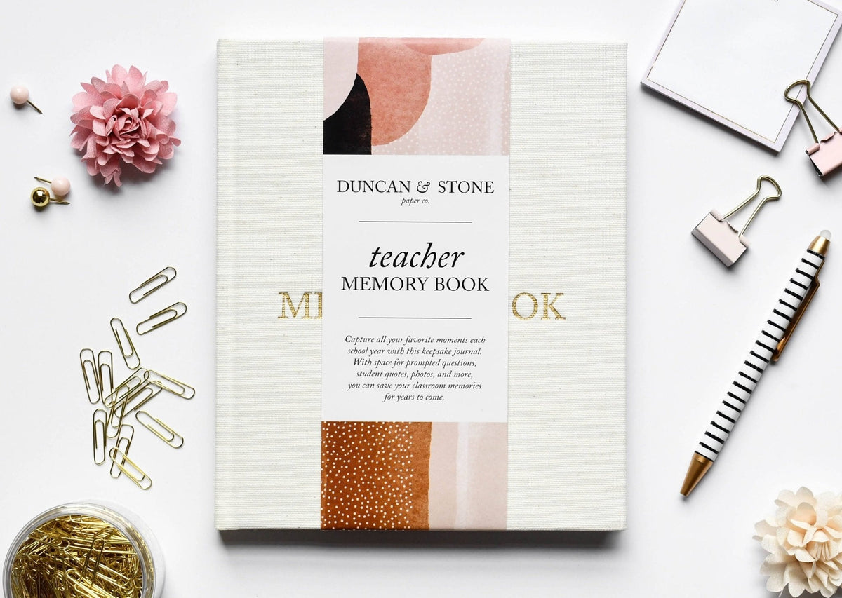 Teacher memory book by Duncan & Stone on a white surface with stationery items.