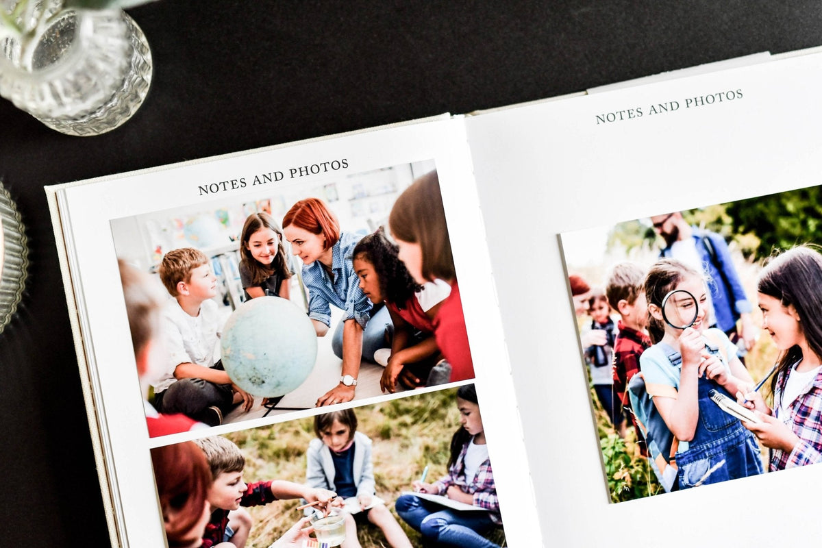 Two photo albums open to pages with children's photos on a dark surface.