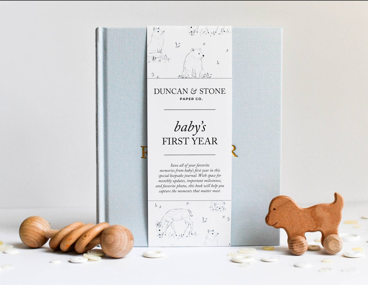 Baby's first year memory book by Duncan & Stone with wooden toys on a light background