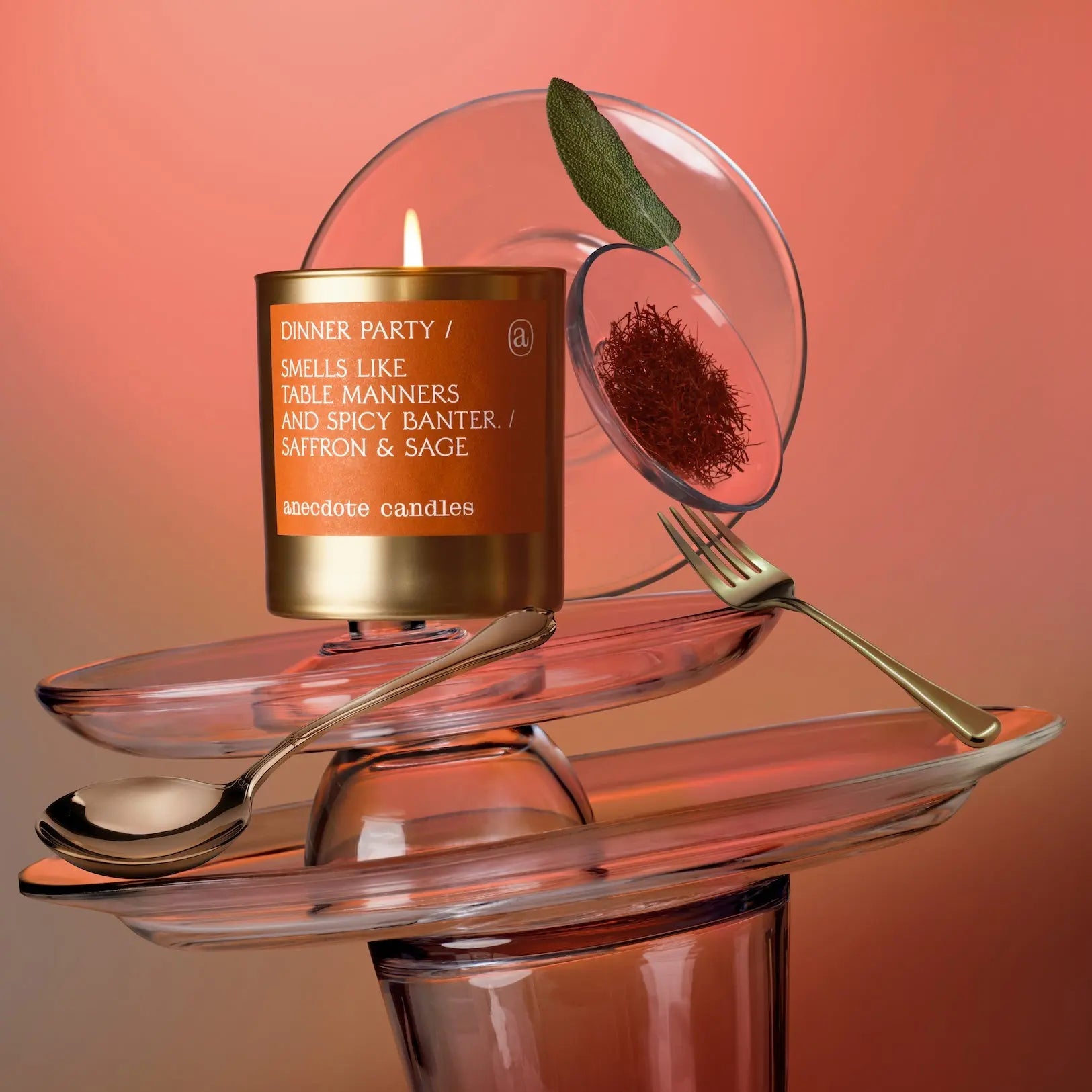Candle labeled 'Dinner Party' on a decorative glass stand with saffron and sage.