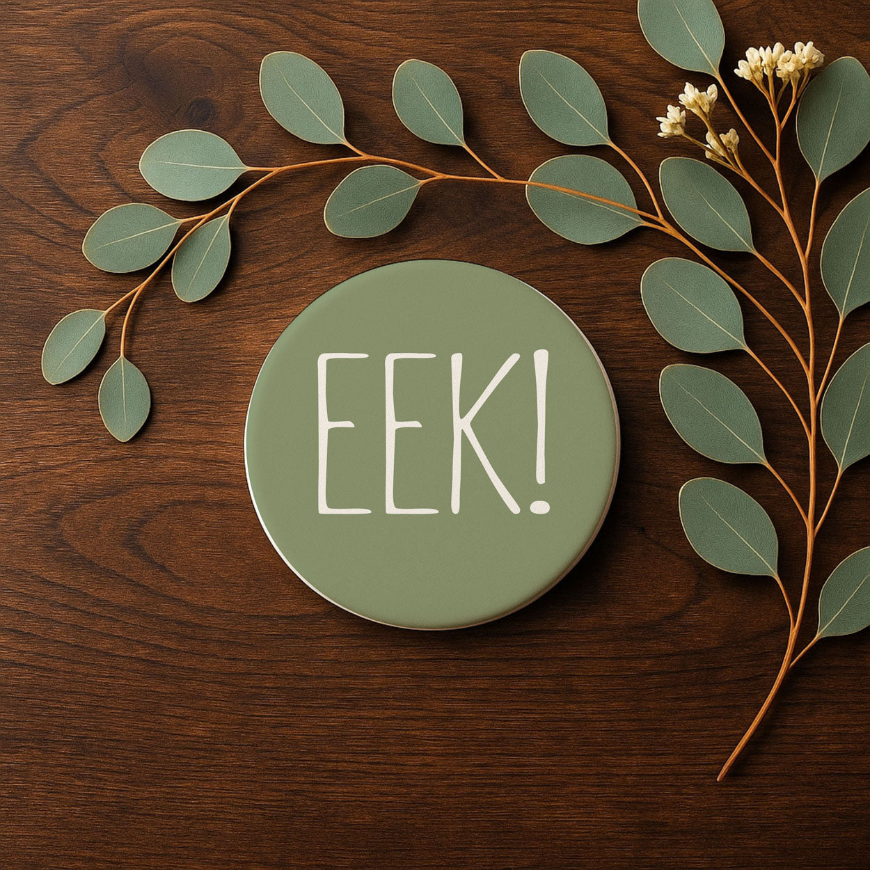 Green round sign with 'Eek!' on a wooden surface with leaves and branches.