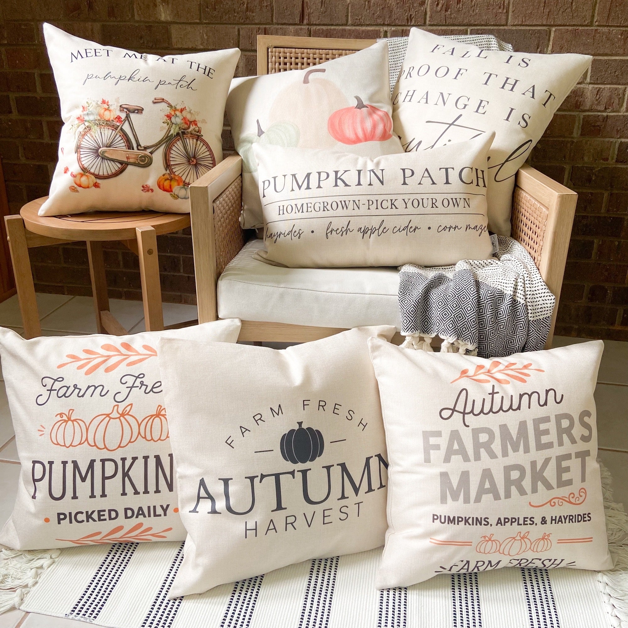Set of fall-themed pillows on a chair with a brick wall background