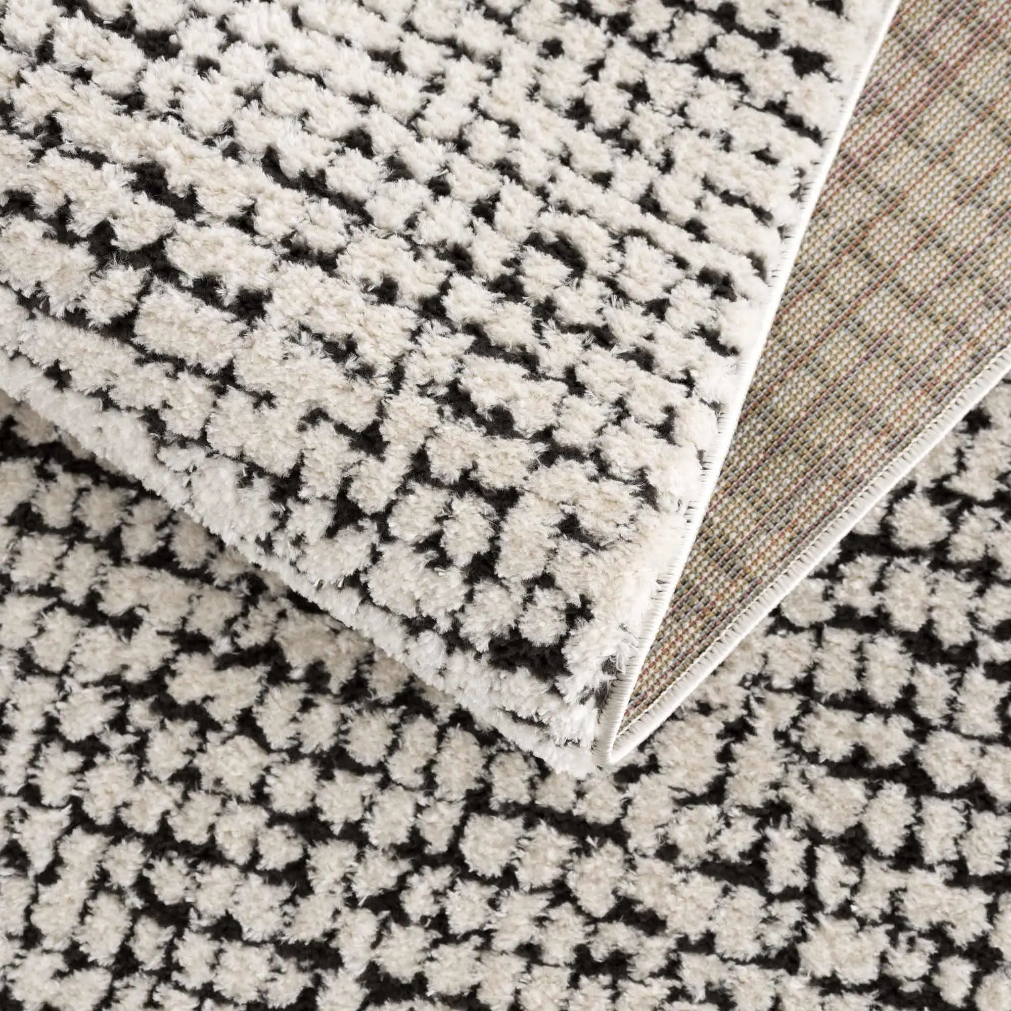 Cozy farmhouse area rug with black and cream geometric pattern, soft shag texture, and woven backing