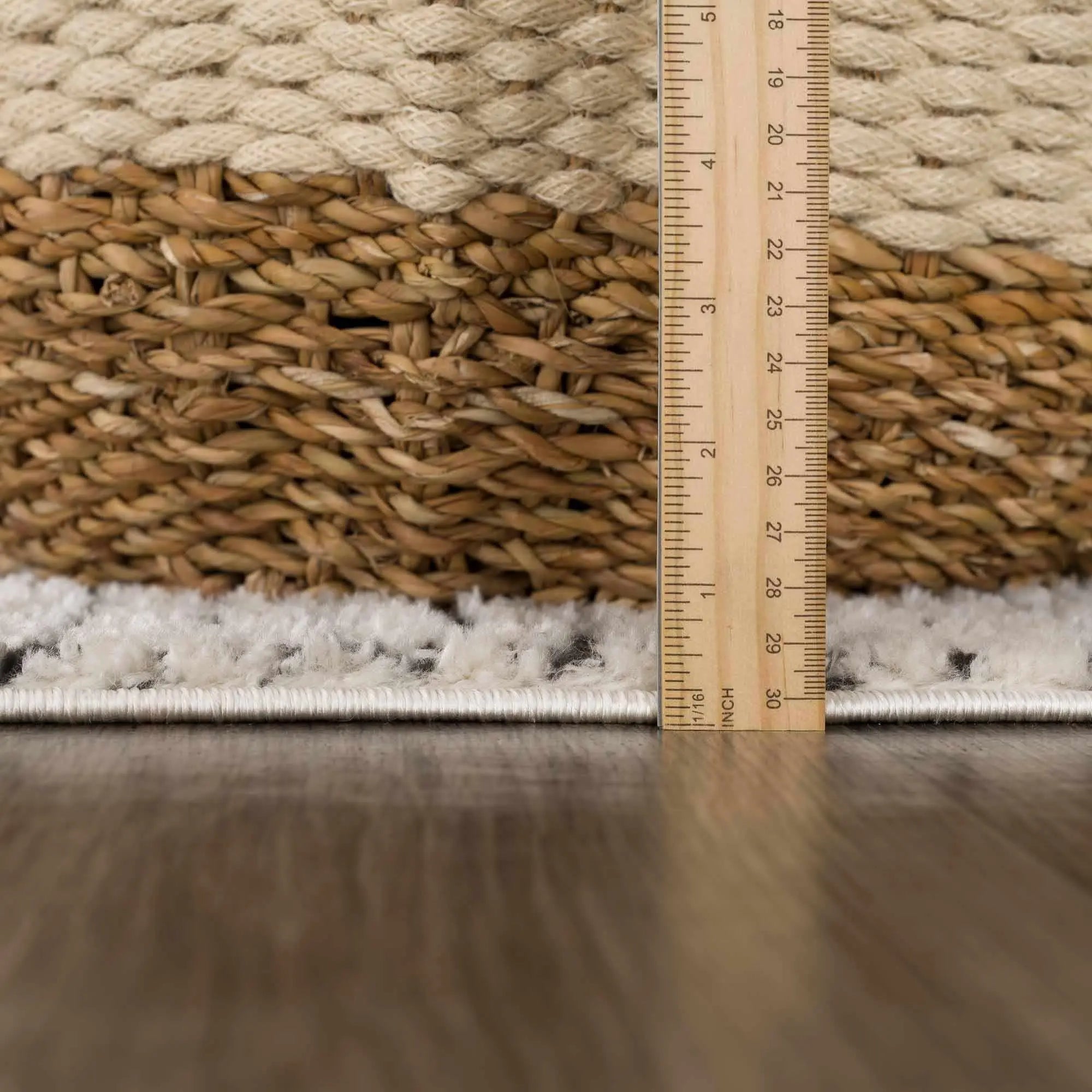 Cozy woven basket with natural fibers, soft white rug edge, and wooden ruler on hardwood floor
