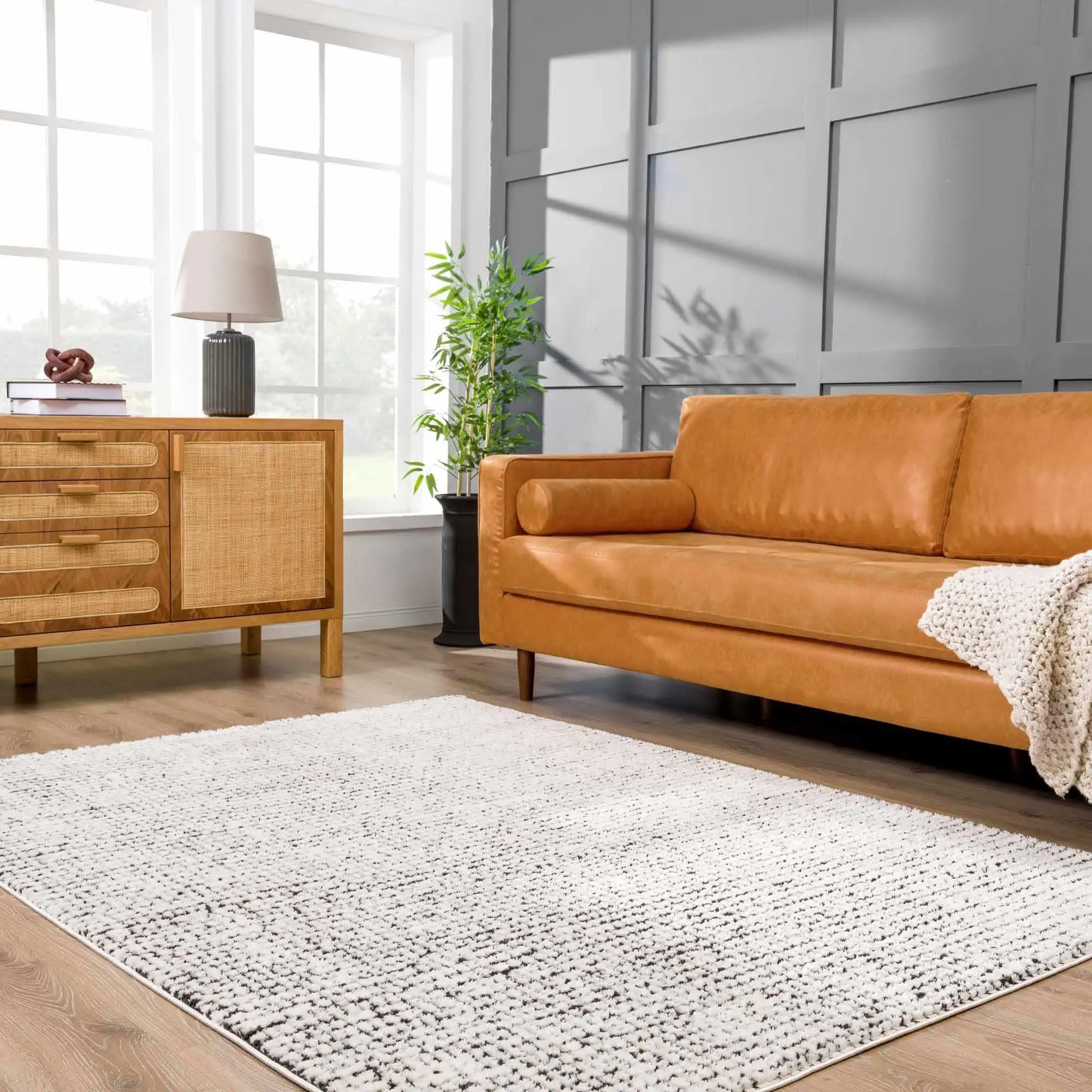 Cozy living room with tan leather sofa, white textured rug, and wooden sideboard for farmhouse decor