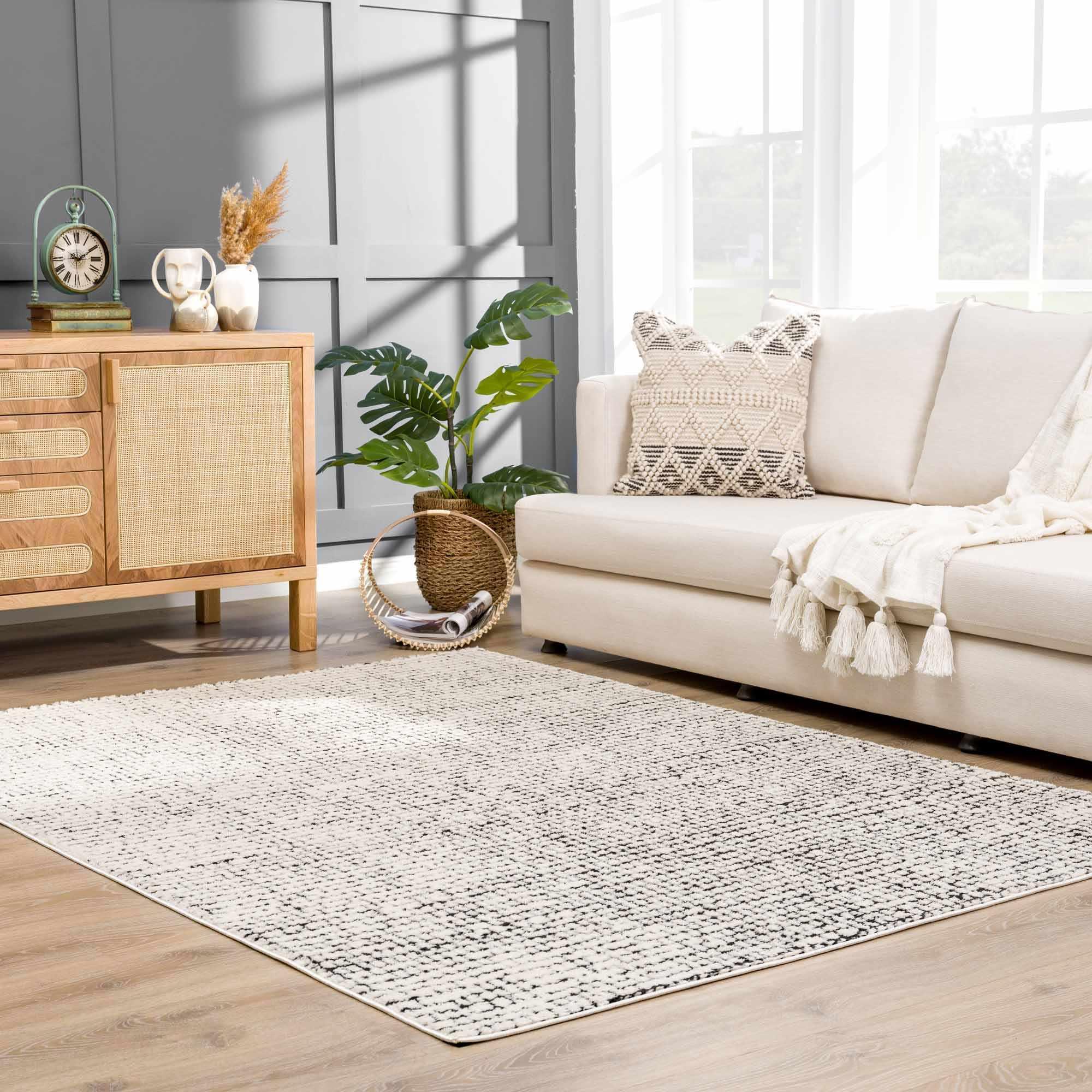 Cozy farmhouse living room with neutral rug, cream sofa, woven sideboard, and tassel throw blanket