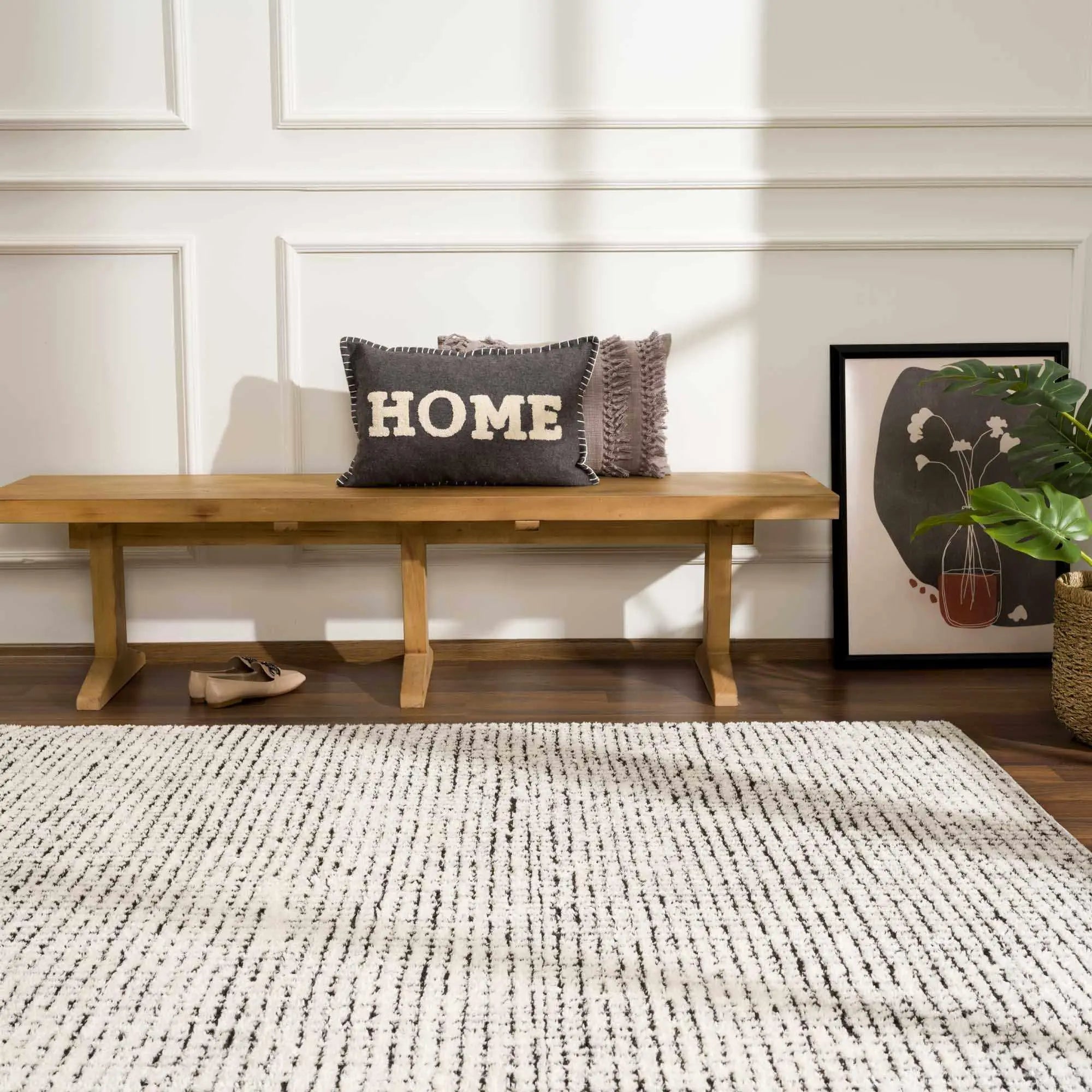 Cozy farmhouse entryway with wooden bench, 'HOME' pillow, and striped rug for warm cottage-style decor