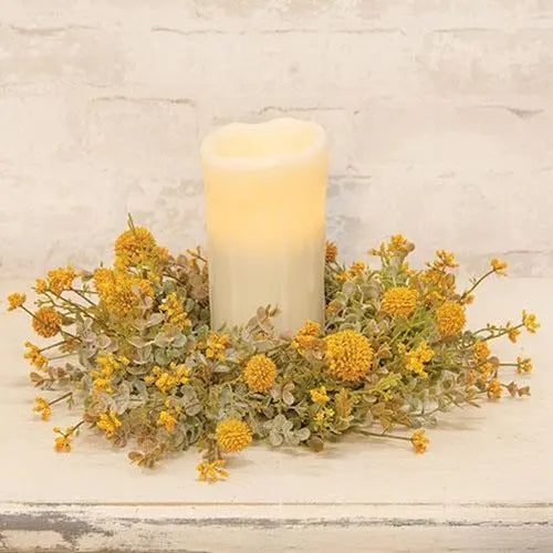 Candle surrounded by yellow flowers on a textured surface
