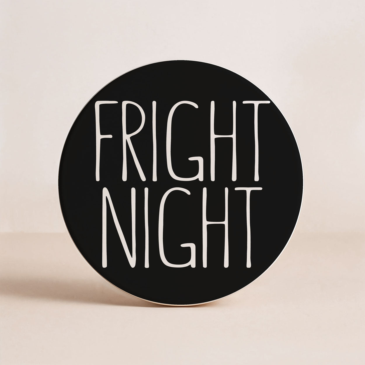 Round black sign with 'Fright Night' text on a beige background