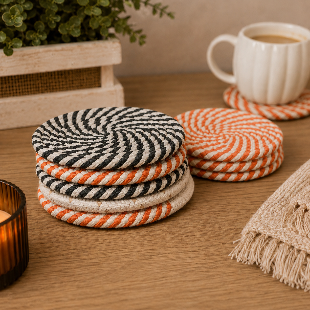 Stack of striped coasters on a wooden surface with a cup and plant in the background.