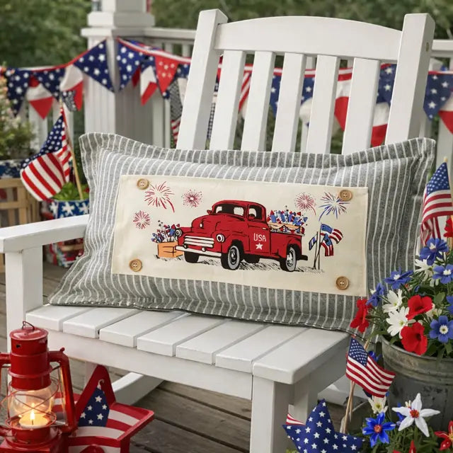 Decorative pillow with a red truck design on a white bench with patriotic decorations.