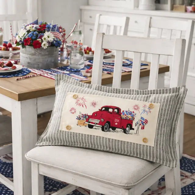 Dining room with a table set for a celebration, featuring a decorative pillow with a red truck design.
