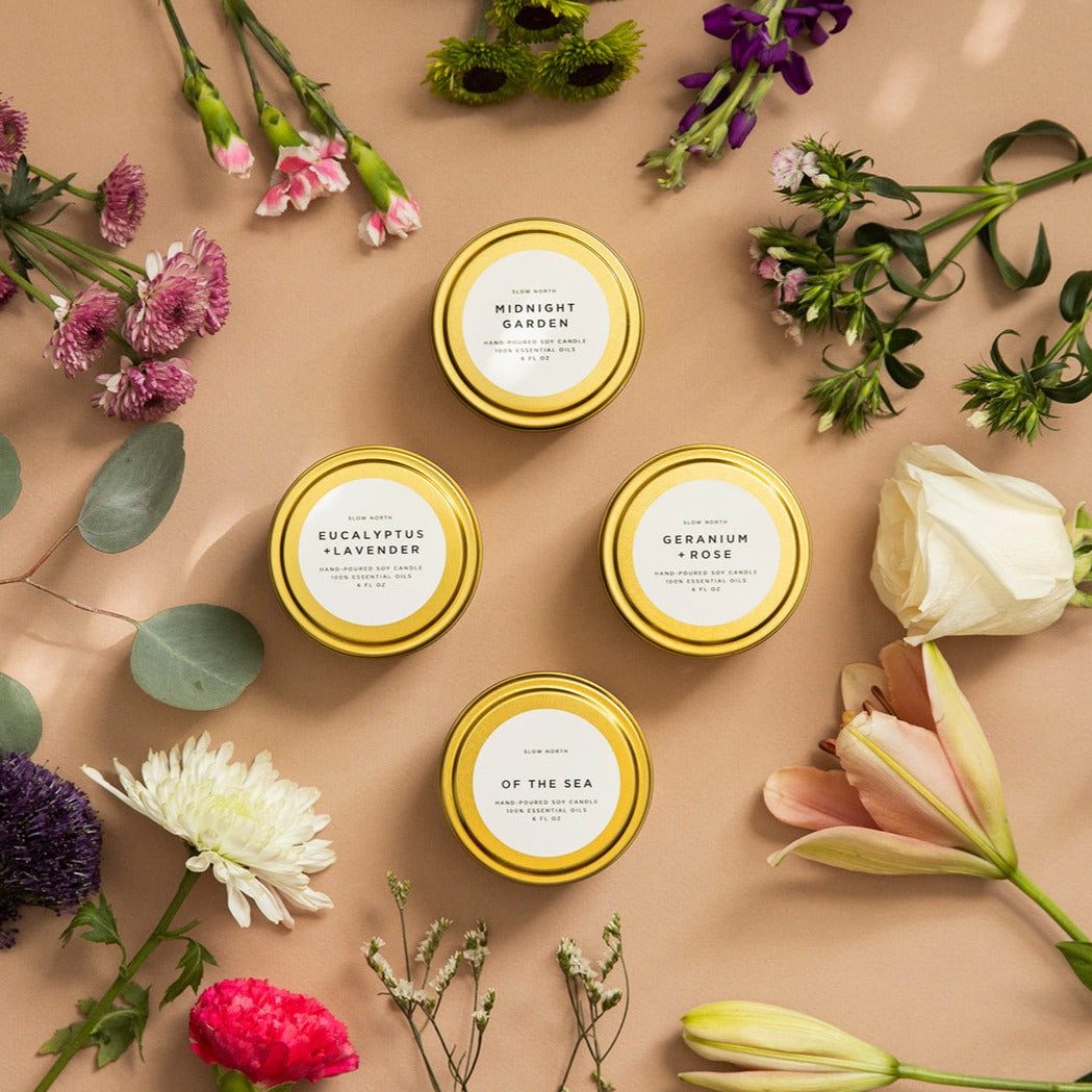 Four yellow tins with labels surrounded by flowers on a beige background