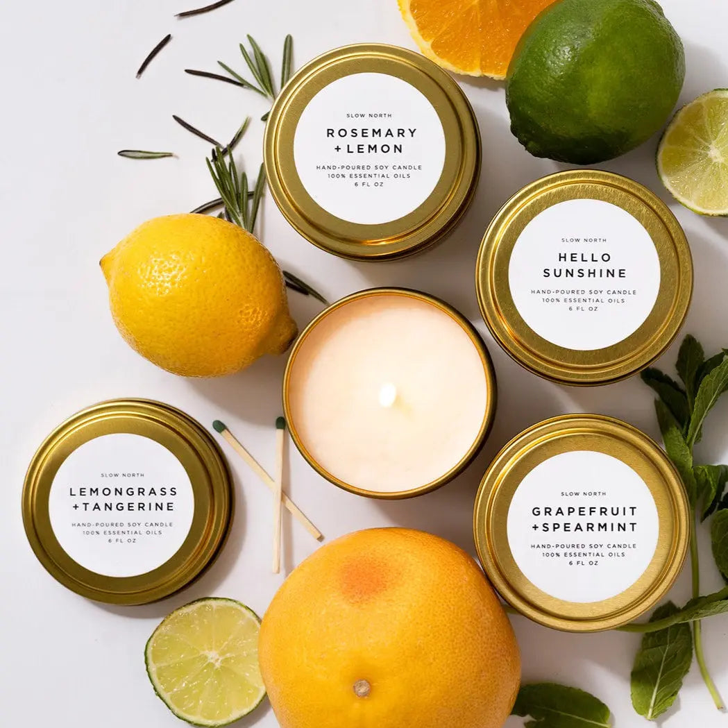 Hand-poured soy candles with citrus & herb scents, gold tins, fresh lemons, limes, rosemary, mint for cozy home decor