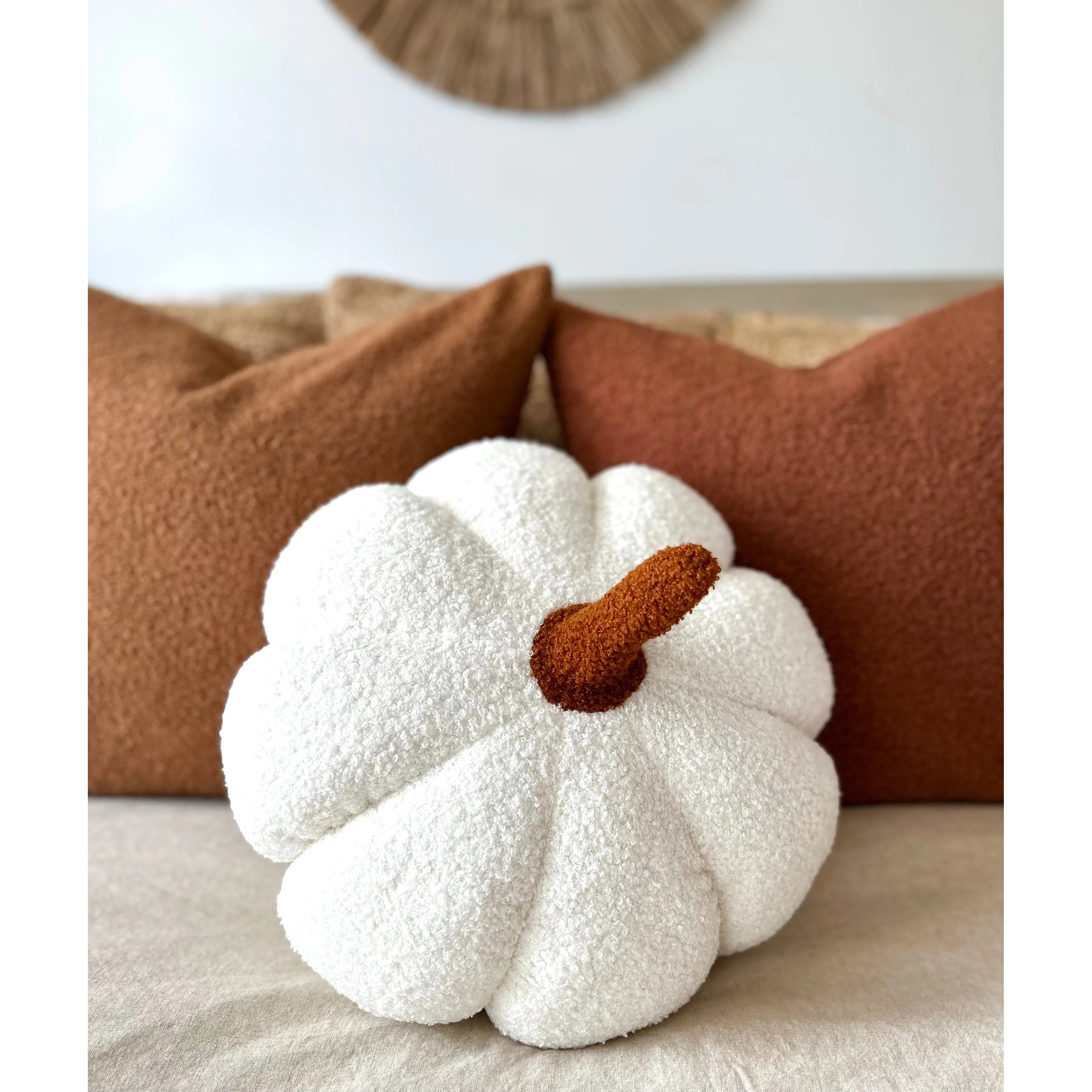 White textured pumpkin pillow with a brown stem on a neutral background
