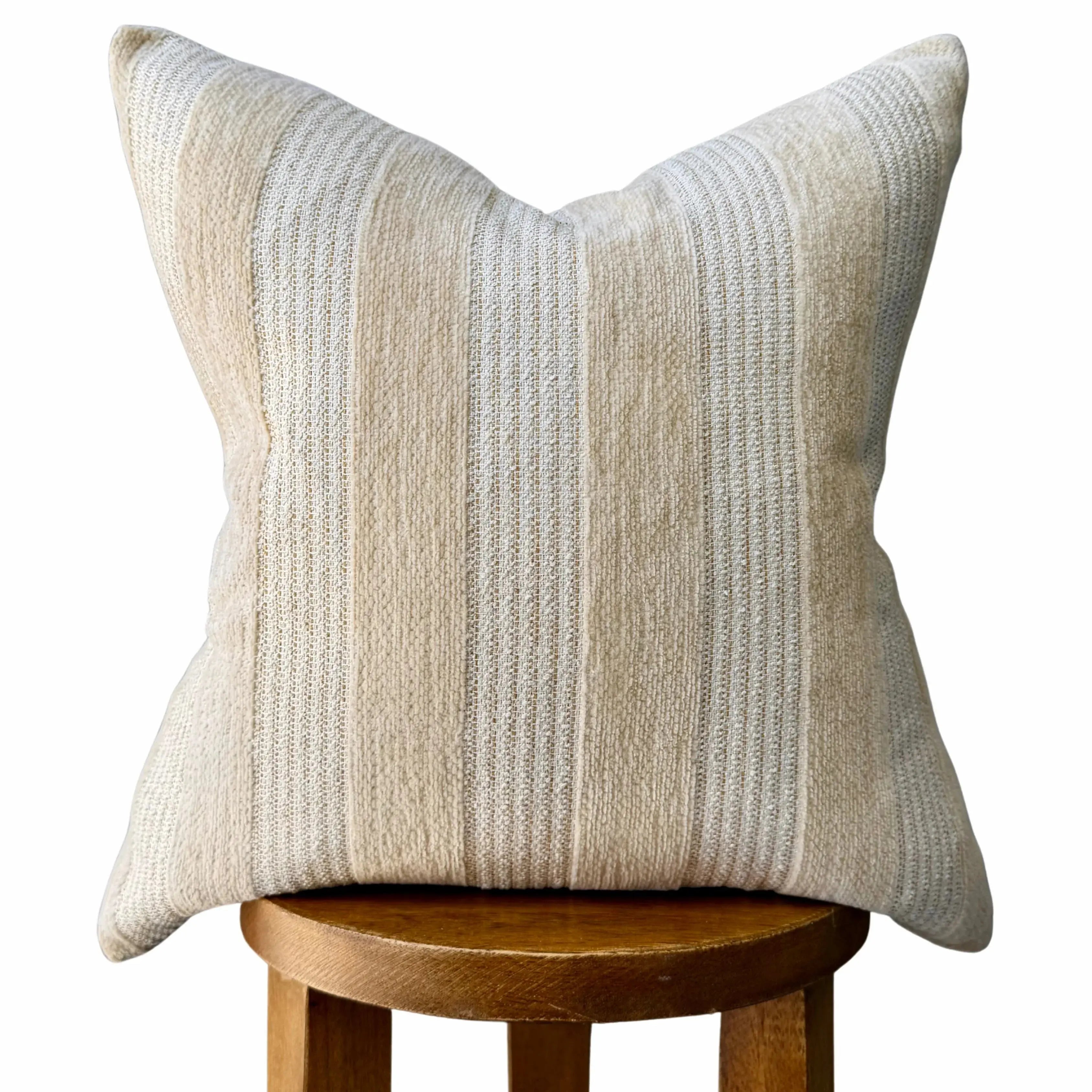 Beige striped throw pillow with textured fabric, perfect for cozy farmhouse or cottage decor on wooden stool
