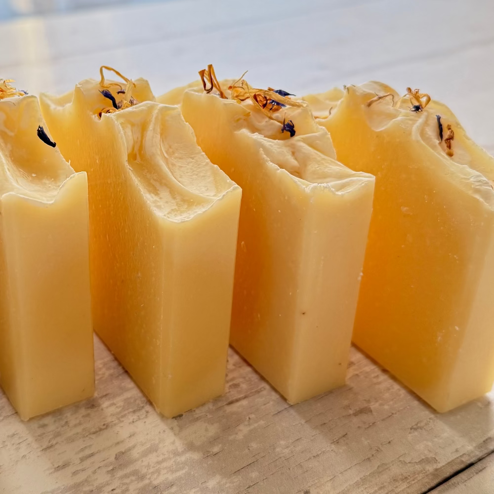 Row of square beeswax bar soap on a wooden surface with a blurred background