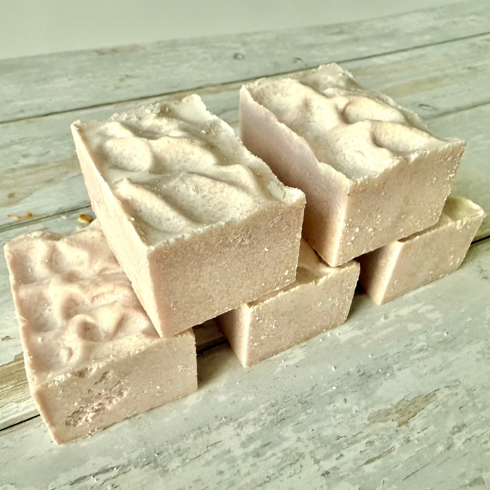 Stack of pink soap bars on a wooden surface