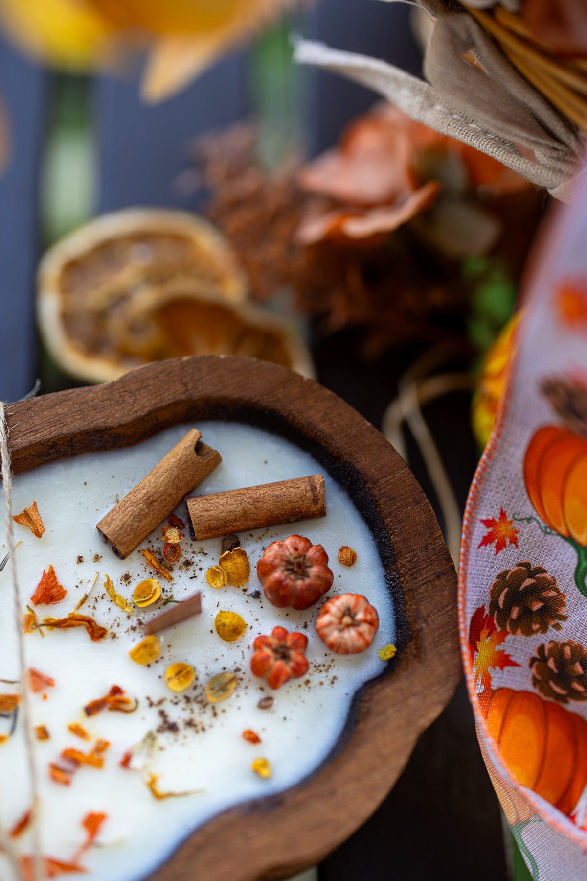 Cup of hot chocolate with cinnamon sticks, nuts, and pumpkin spice on a wooden coaster.