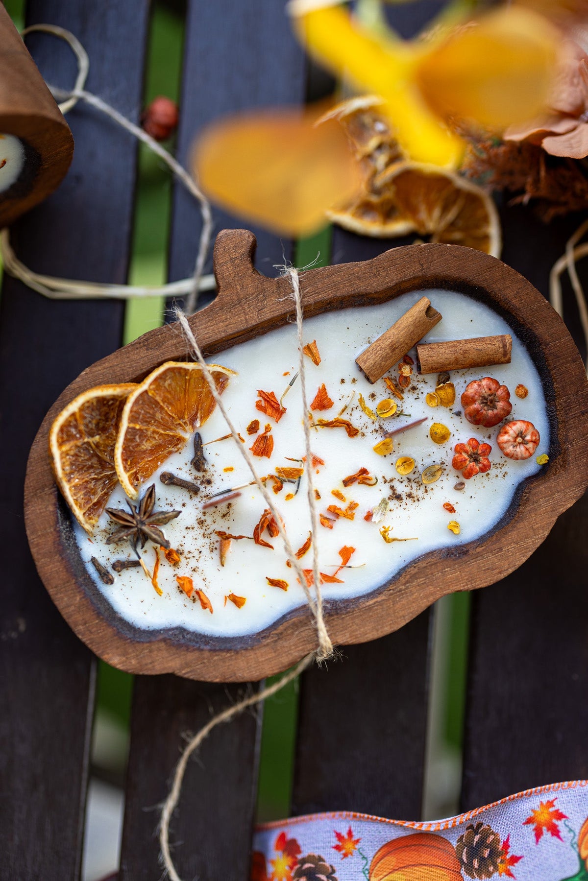 Decorative autumn-themed ornament with spices and oranges on a wooden base.