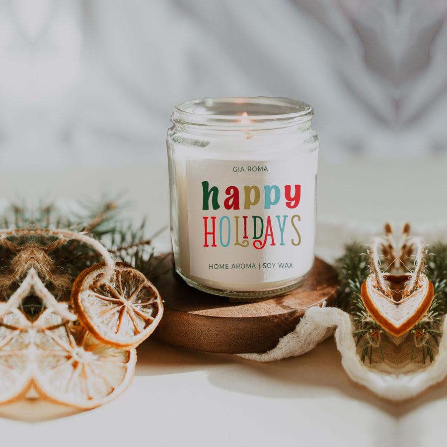 Candle labeled 'happy holidays' with decorative elements on a neutral background