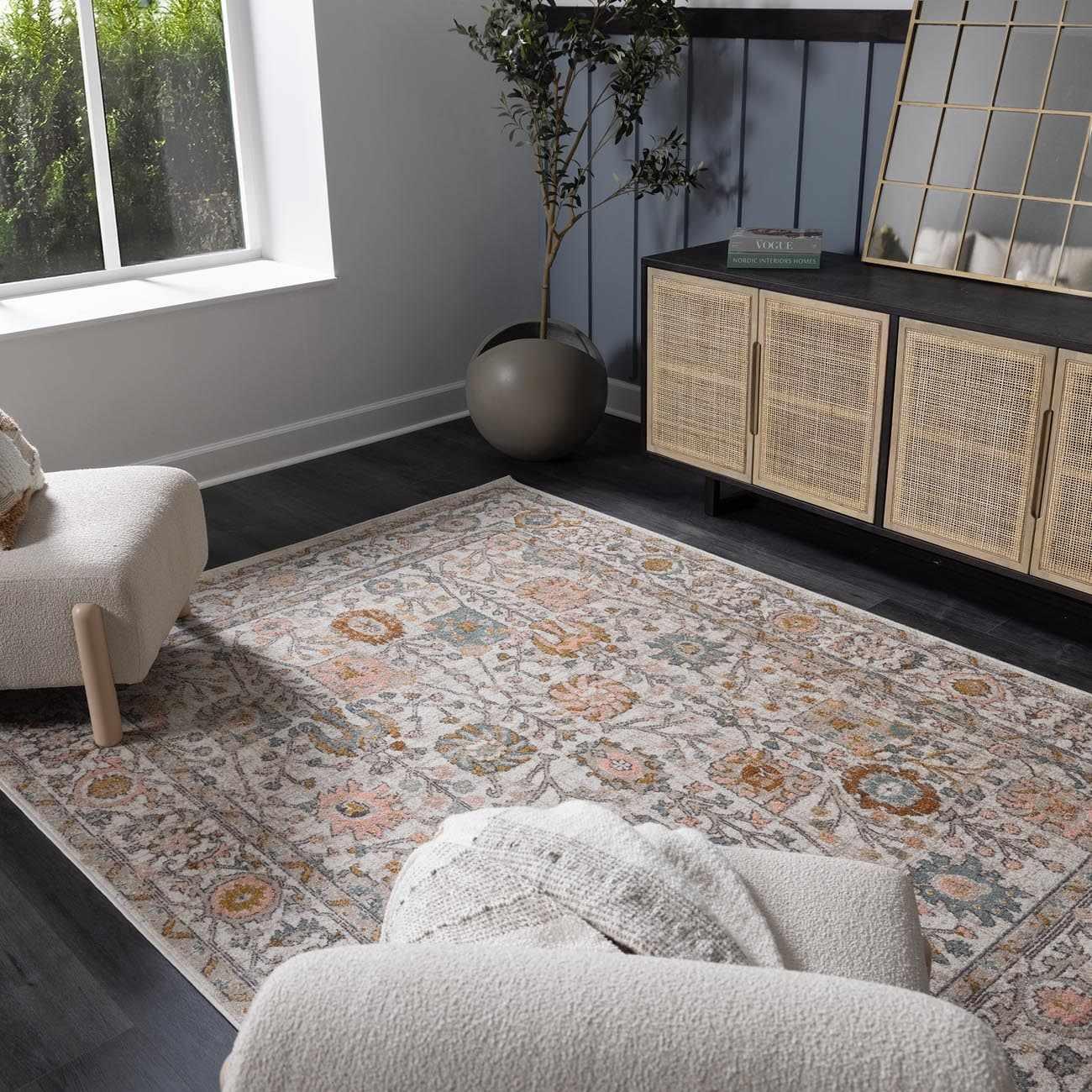 Cozy living room with floral rug, rattan cabinet, and soft armchair for farmhouse decor