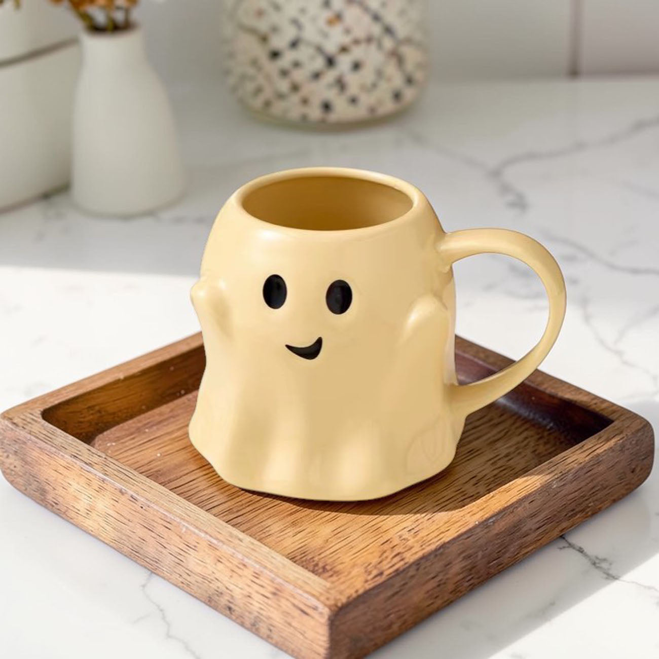 Yellow ghost-shaped mug on a wooden tray with a blurred background