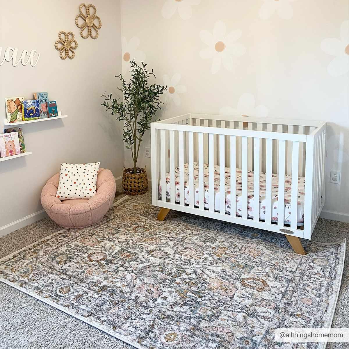 Cozy nursery with white crib, floral rug, and pink chair for baby's peaceful space