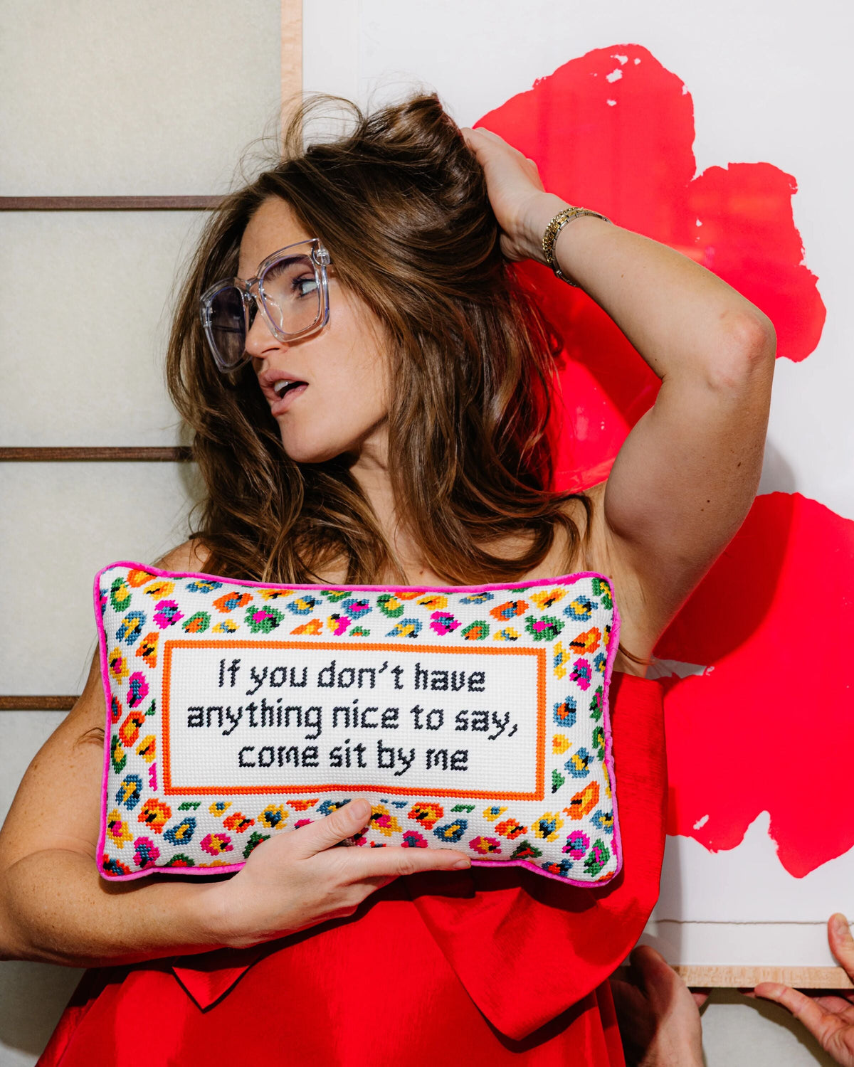Woman holding a colorful pillow with text against a red and white background