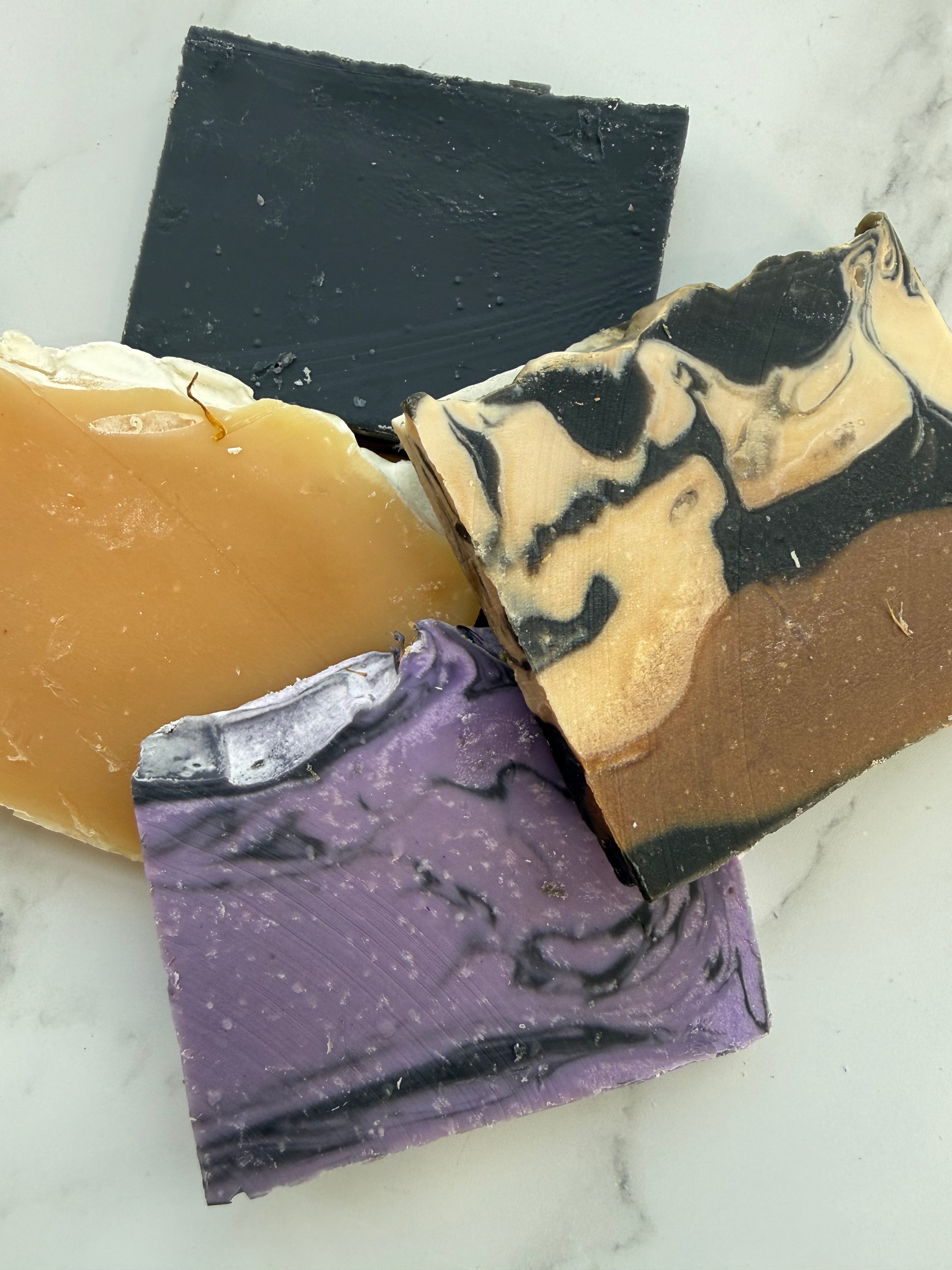 Three bars of soap with different colors and textures on a marble surface
