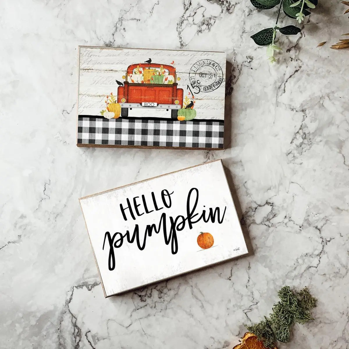 Decorative signs with a truck and 'Hello Pumpkin' text on a marble surface.