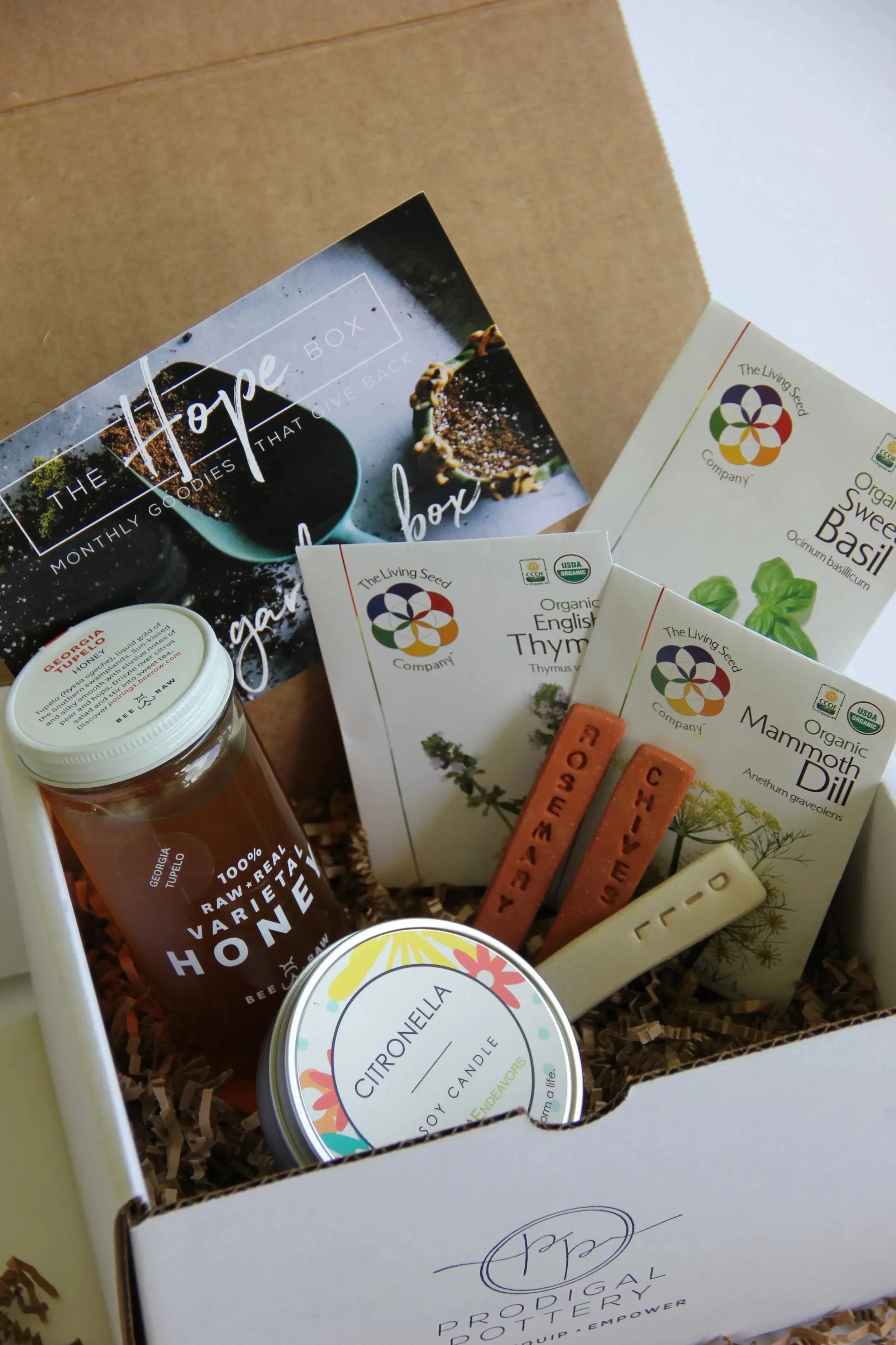 Cozy gift box with raw honey, citronella soy candle, organic herb seeds, and pottery tools for farmhouse home decor
