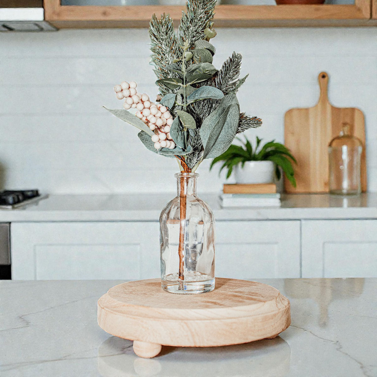 Decorative vase with plants on a wooden stand in a kitchen setting