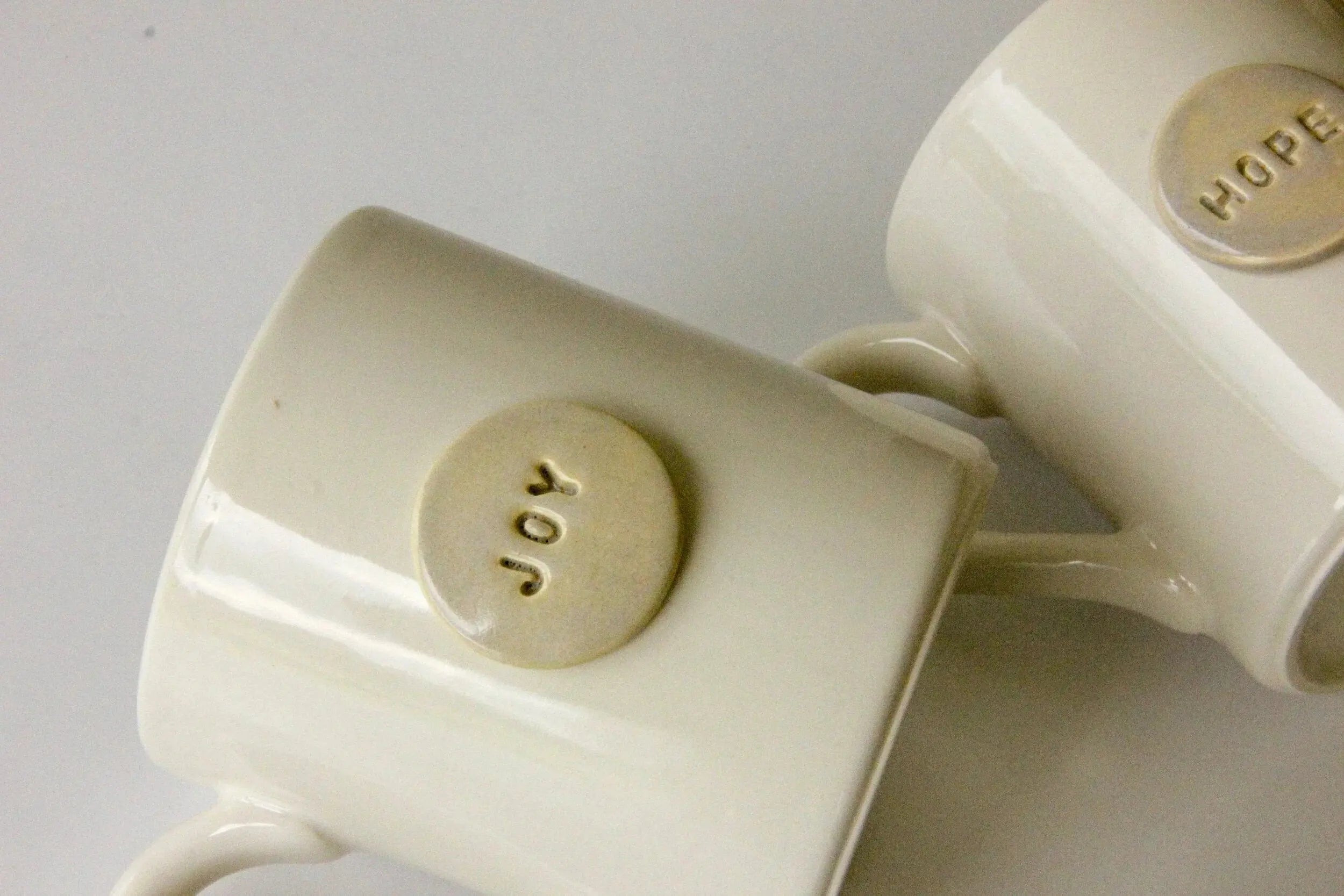Cream ceramic mugs with 'Joy' and 'Hope' embossed, cozy farmhouse home decor