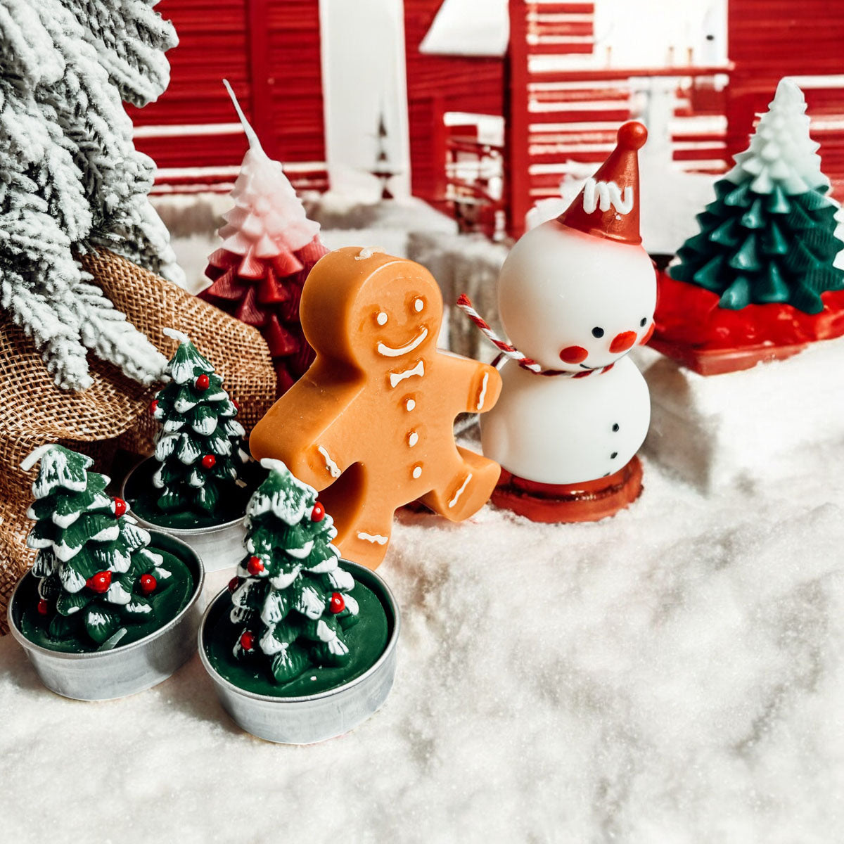 Decorative Christmas scene with gingerbread man, snowman, and miniature trees on a snowy surface.