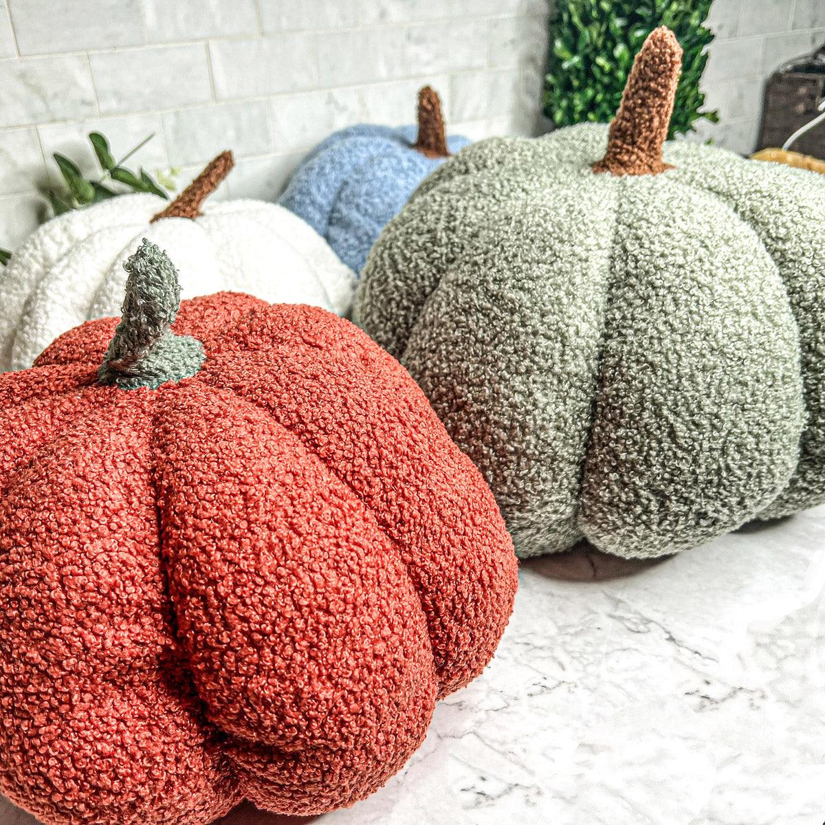 Decorative pumpkins in red, green, and white on a marble surface with a blurred background.