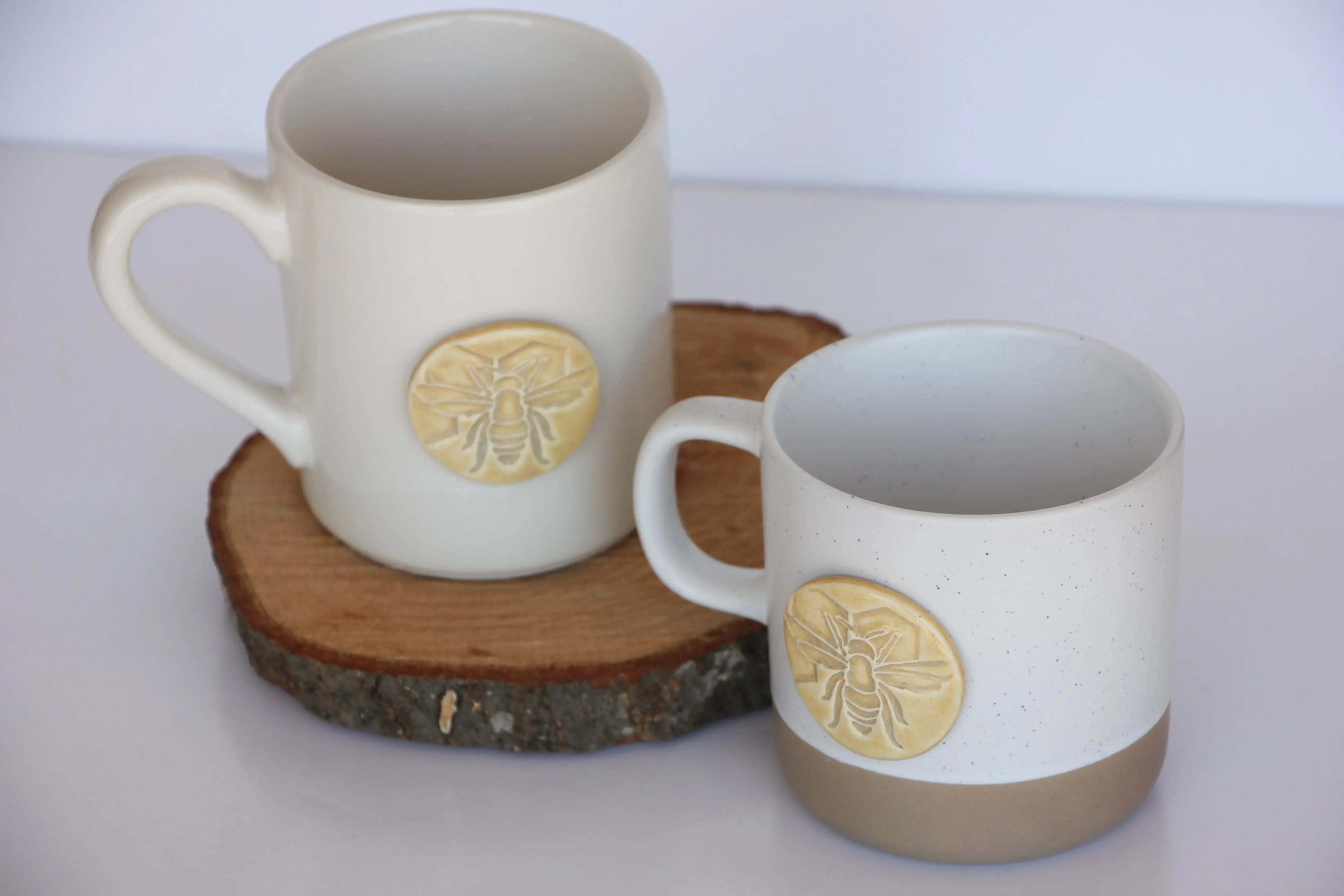 Handcrafted ceramic mugs with bee motifs, farmhouse style home decor on wood slice